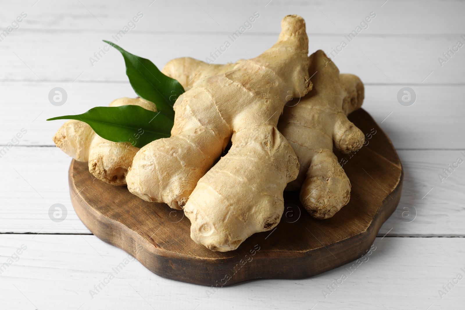 Photo of Fresh ginger with leaves on white wooden table