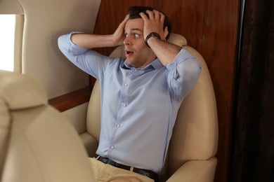 Scared young man suffering from aviophobia in airplane