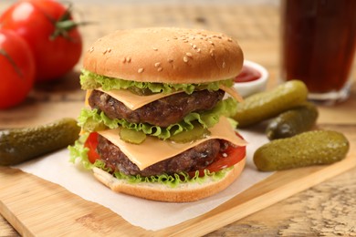 Tasty hamburger with patties and pickles on wooden table, closeup