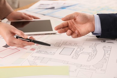 Photo of Professional cartographers working with cadastral map at table, closeup