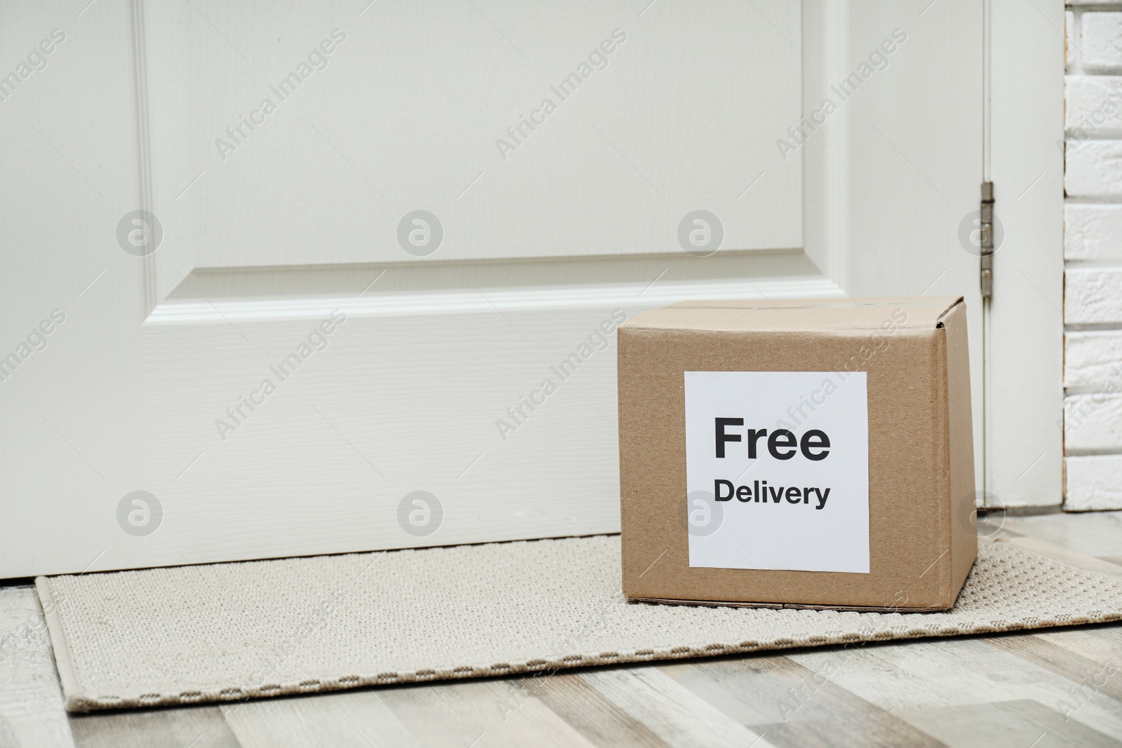 Photo of Parcel with sticker Free Delivery on rug indoors, space for text. Courier service