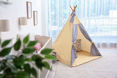 Photo of Cozy baby room interior with play tent and toys