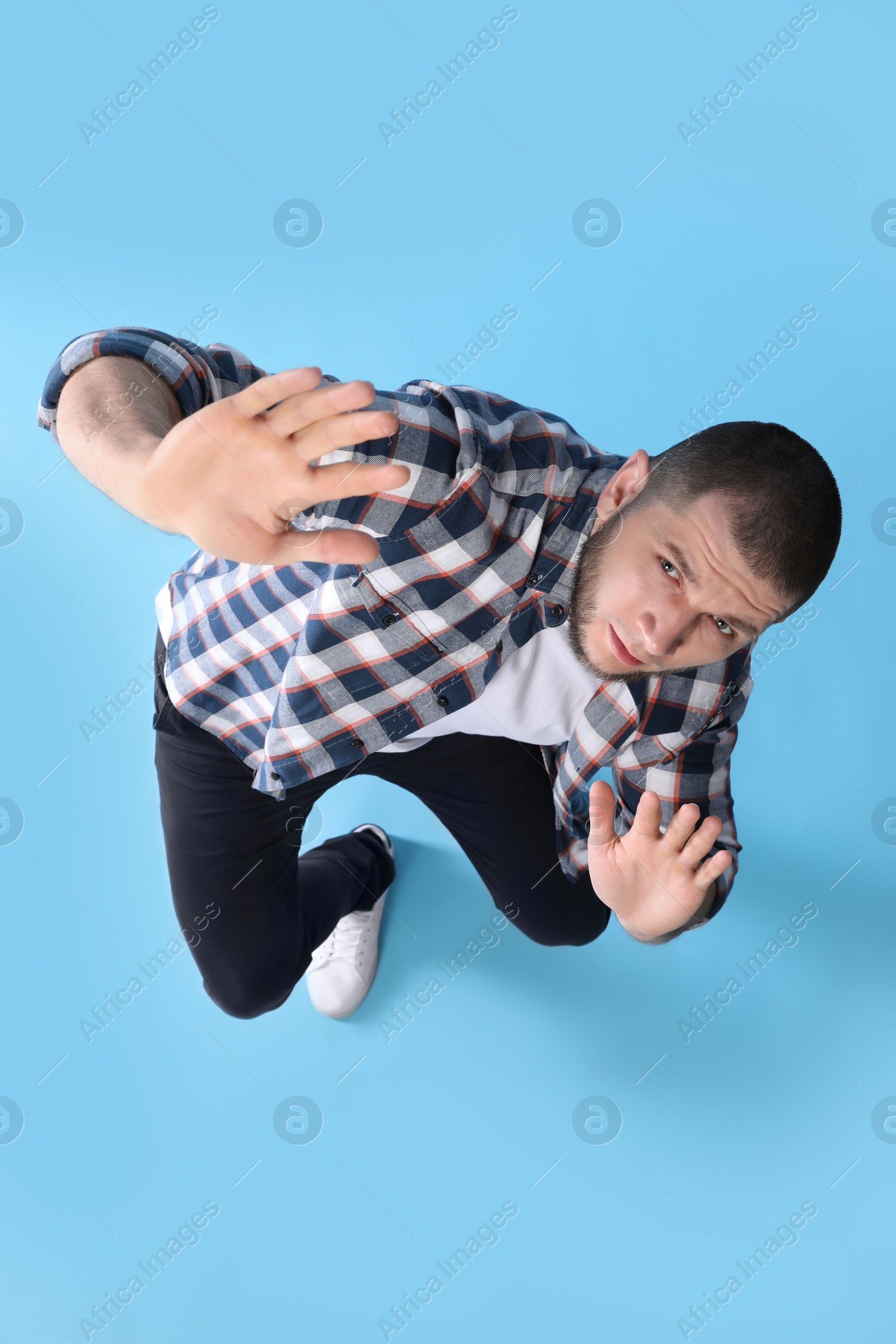 Photo of Man evading something on light blue background, above view
