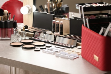 Photo of Different makeup products and accessories on dressing table in room interior