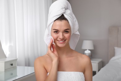 Photo of Beautiful young woman with hair wrapped in towel cleaning her face at home