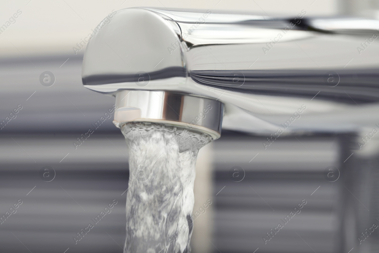 Photo of Water flowing from tap on blurred background, closeup