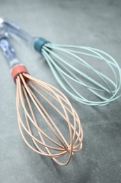 Photo of Two whisks on gray table, closeup. Kitchen tool