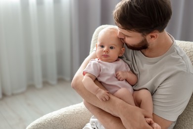 Photo of Father with his cute baby in armchair at home, space for text