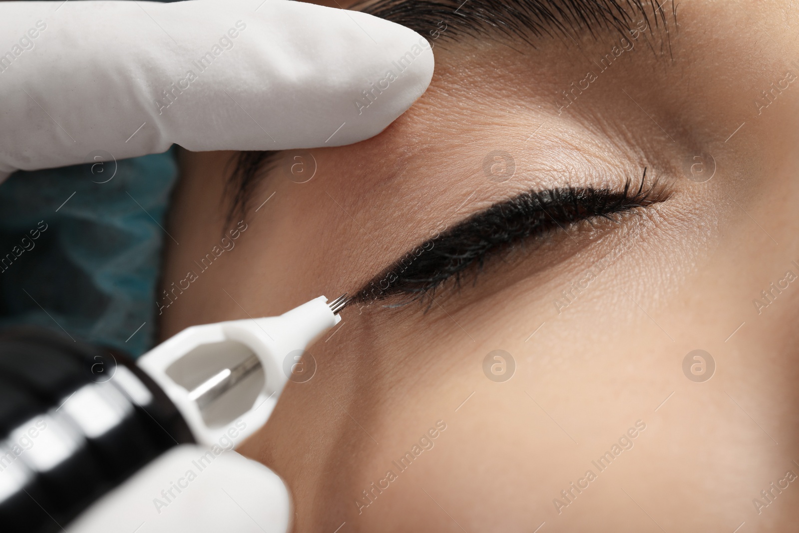 Photo of Young woman undergoing procedure of permanent eyeliner makeup, closeup