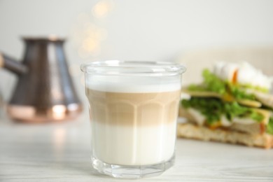 Glass of delicious coffee on white wooden table, closeup