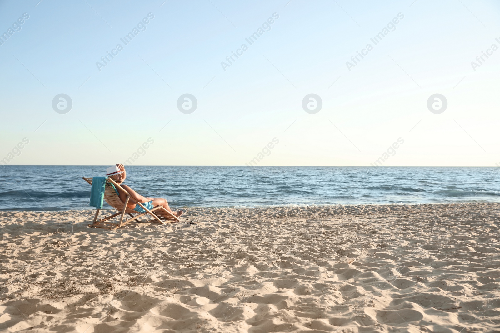 Photo of Young man relaxing in deck chair on beach near sea