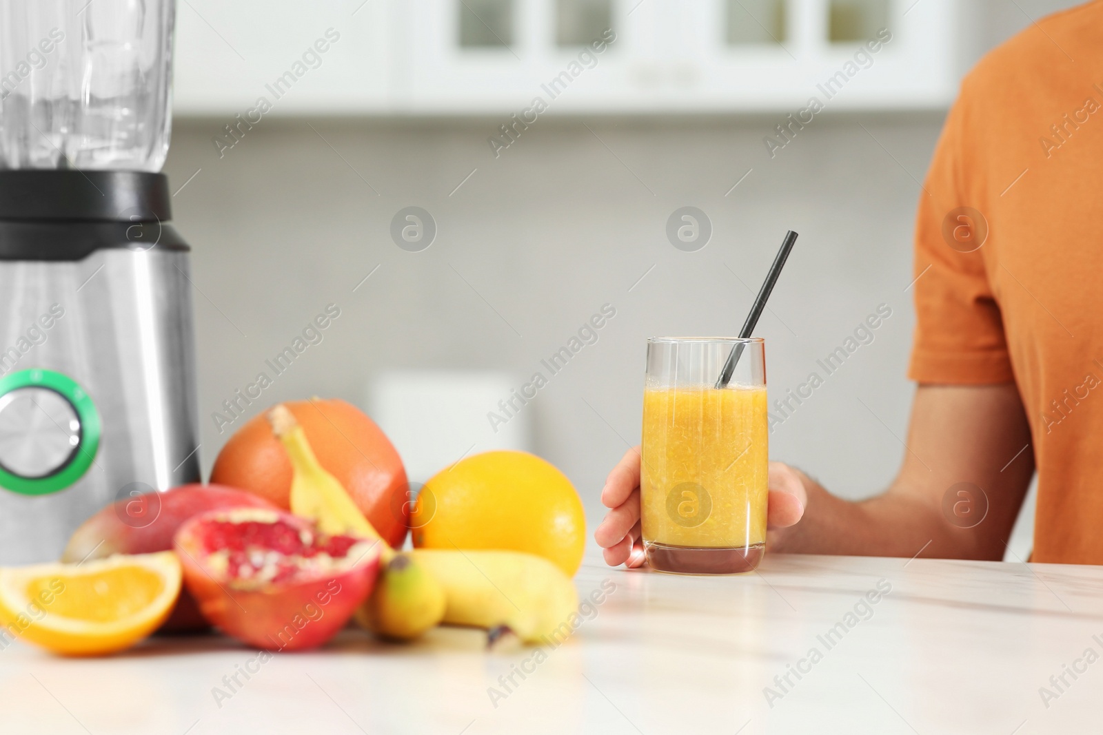 Photo of Man with delicious smoothie at white marble table in kitchen, closeup