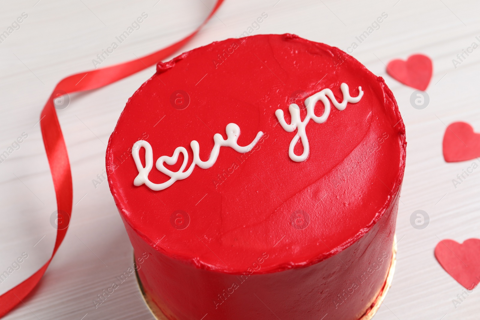 Photo of Bento cake with text Love You and paper hearts on white wooden table, closeup. St. Valentine's day surprise