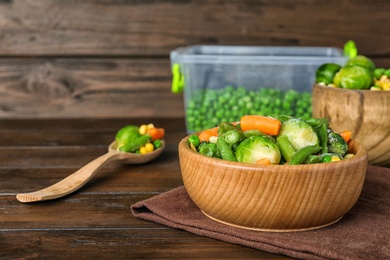 Bowl with different frozen vegetables on wooden table