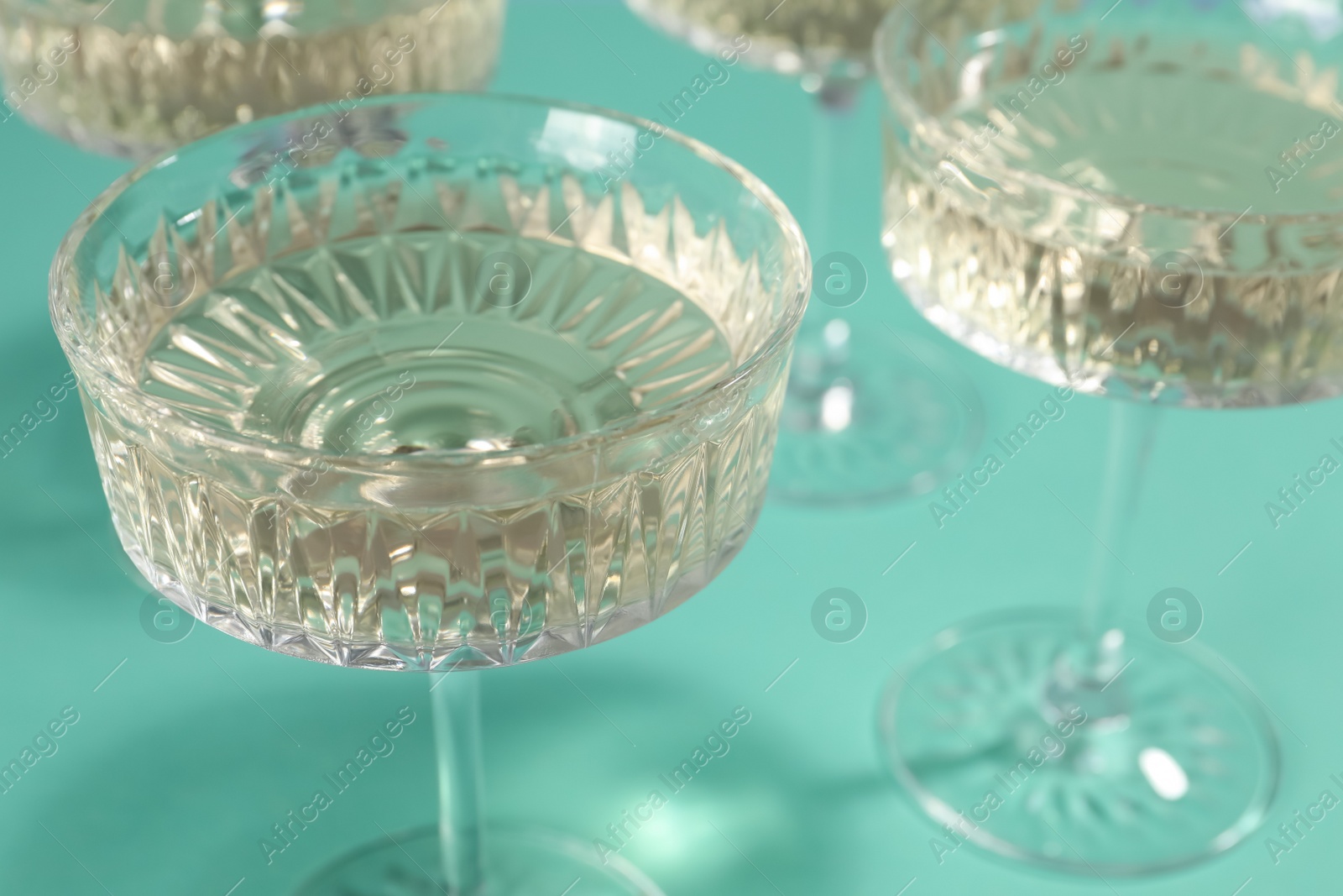 Photo of Glasses of expensive white wine on turquoise background, closeup