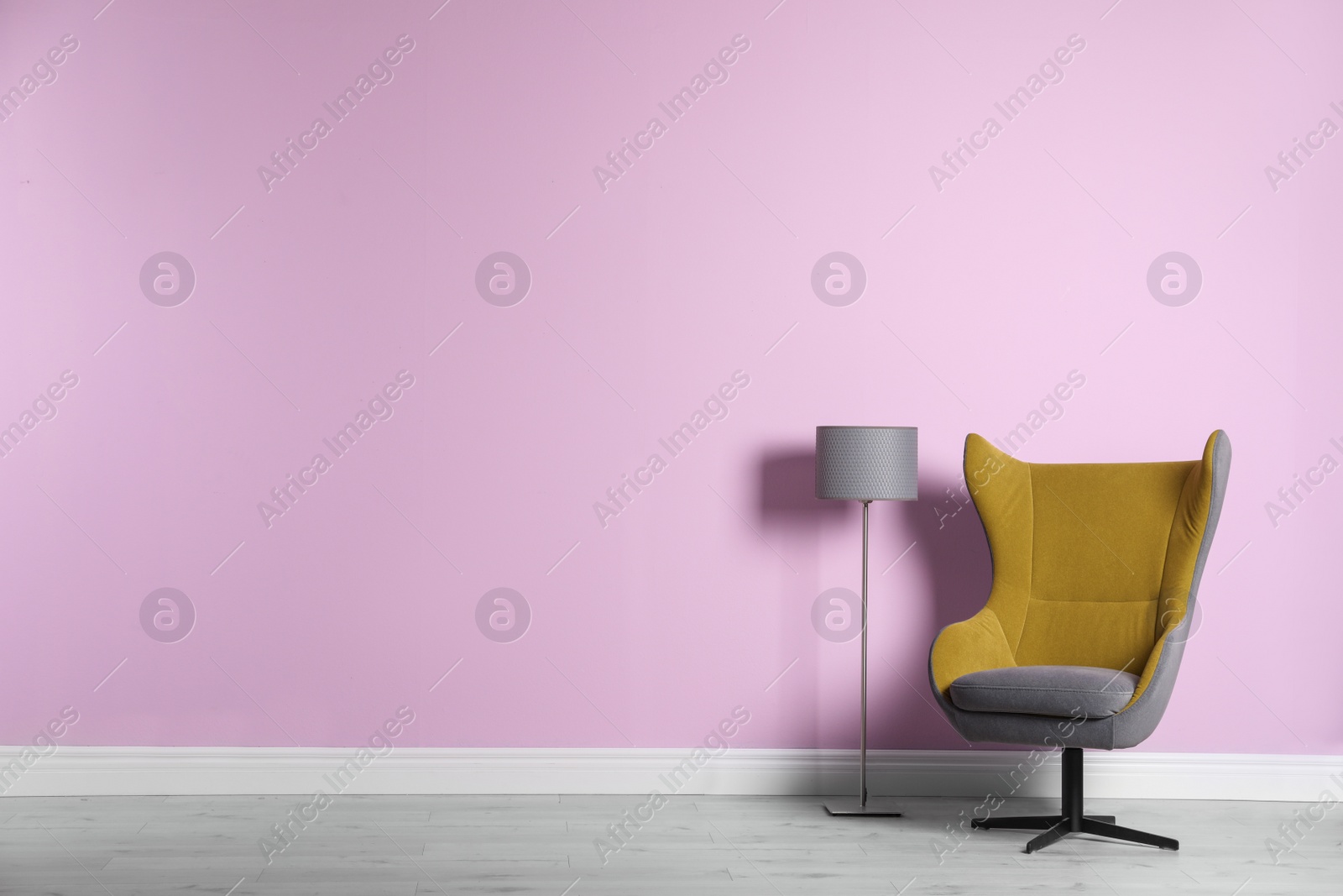 Photo of Comfortable armchair and lamp near color wall with space for text. Interior element