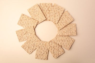 Photo of Fresh crunchy crispbreads on beige background, flat lay