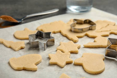 Photo of Cutters and raw Christmas cookies on table. Festive treats