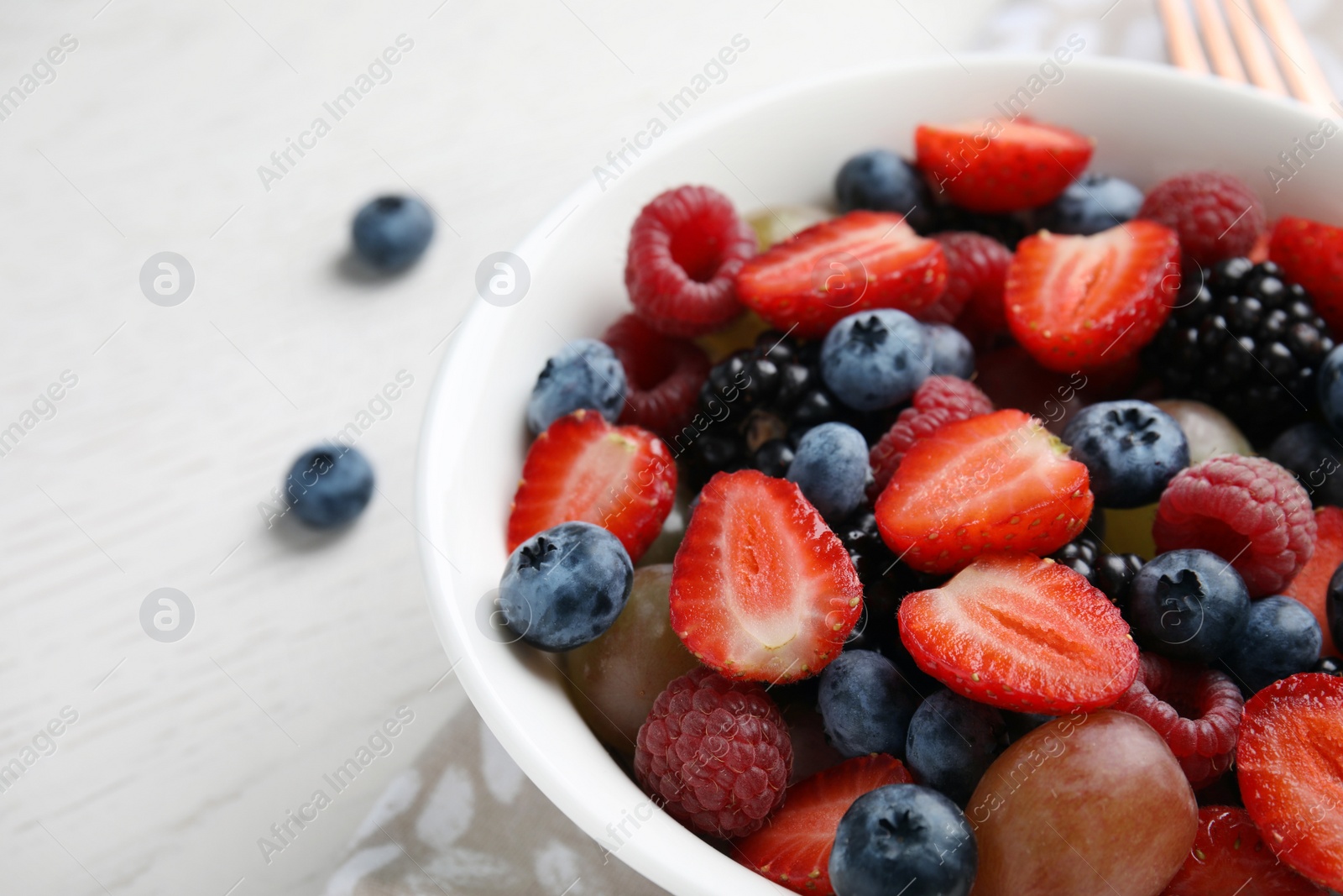 Photo of Fresh tasty fruit salad on white wooden table, closeup