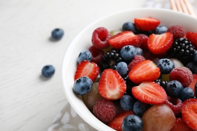 Photo of Fresh tasty fruit salad on white wooden table, closeup