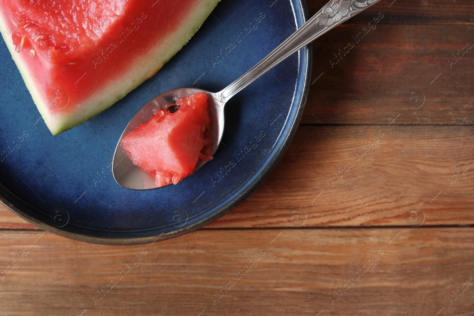 Photo of Sliced fresh juicy watermelon and spoon on wooden table, top view. Space for text