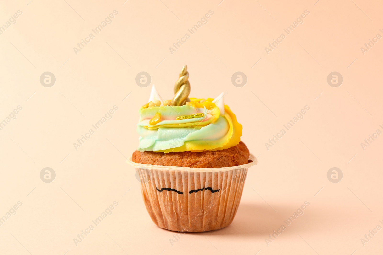 Photo of Cute sweet unicorn cupcake on beige background