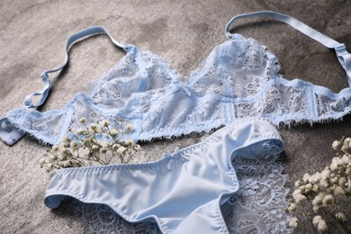 Elegant light blue women's underwear and gypsophila flowers on grey background