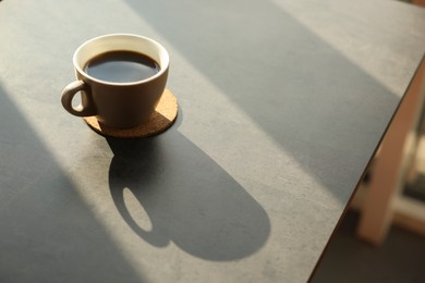 Photo of Cup of delicious coffee on grey table indoors, space for text