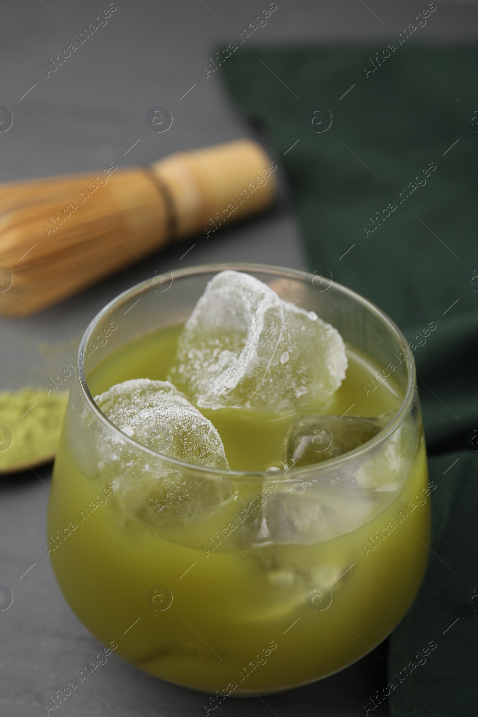 Photo of Glass of delicious iced green matcha tea on grey table, closeup. Space for text