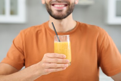Handsome man with delicious smoothie indoors, closeup