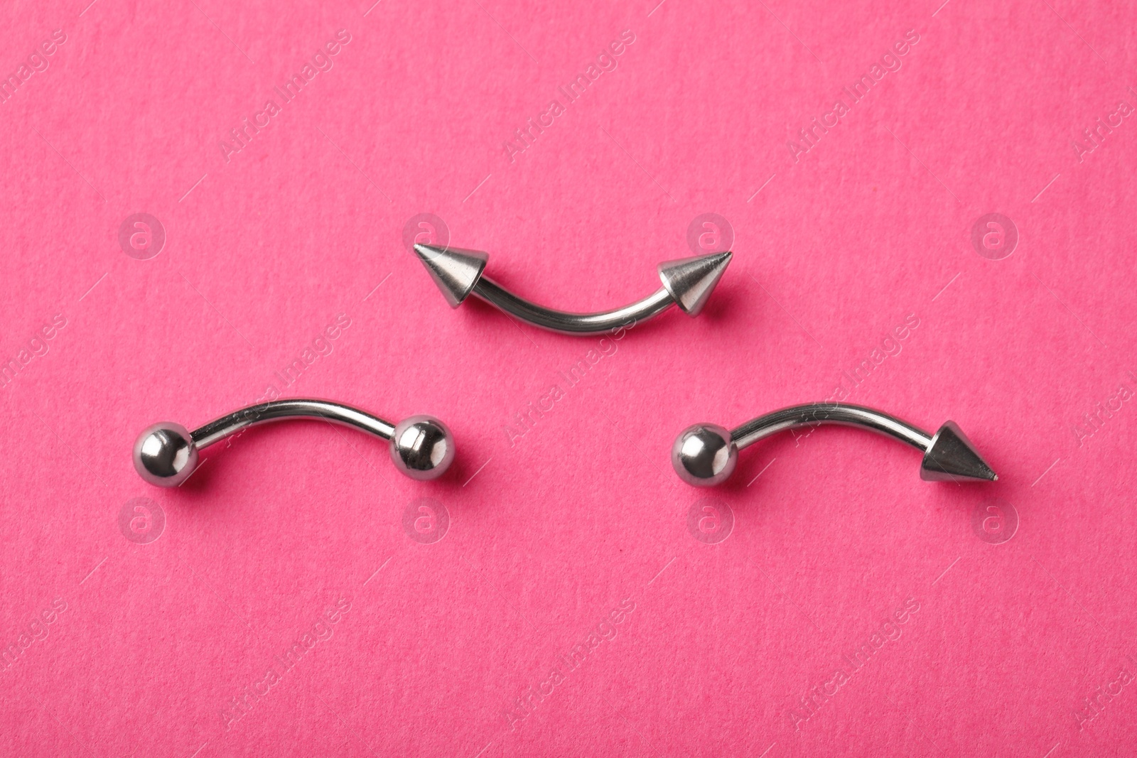 Photo of Stylish piercing jewelry on pink background, flat lay