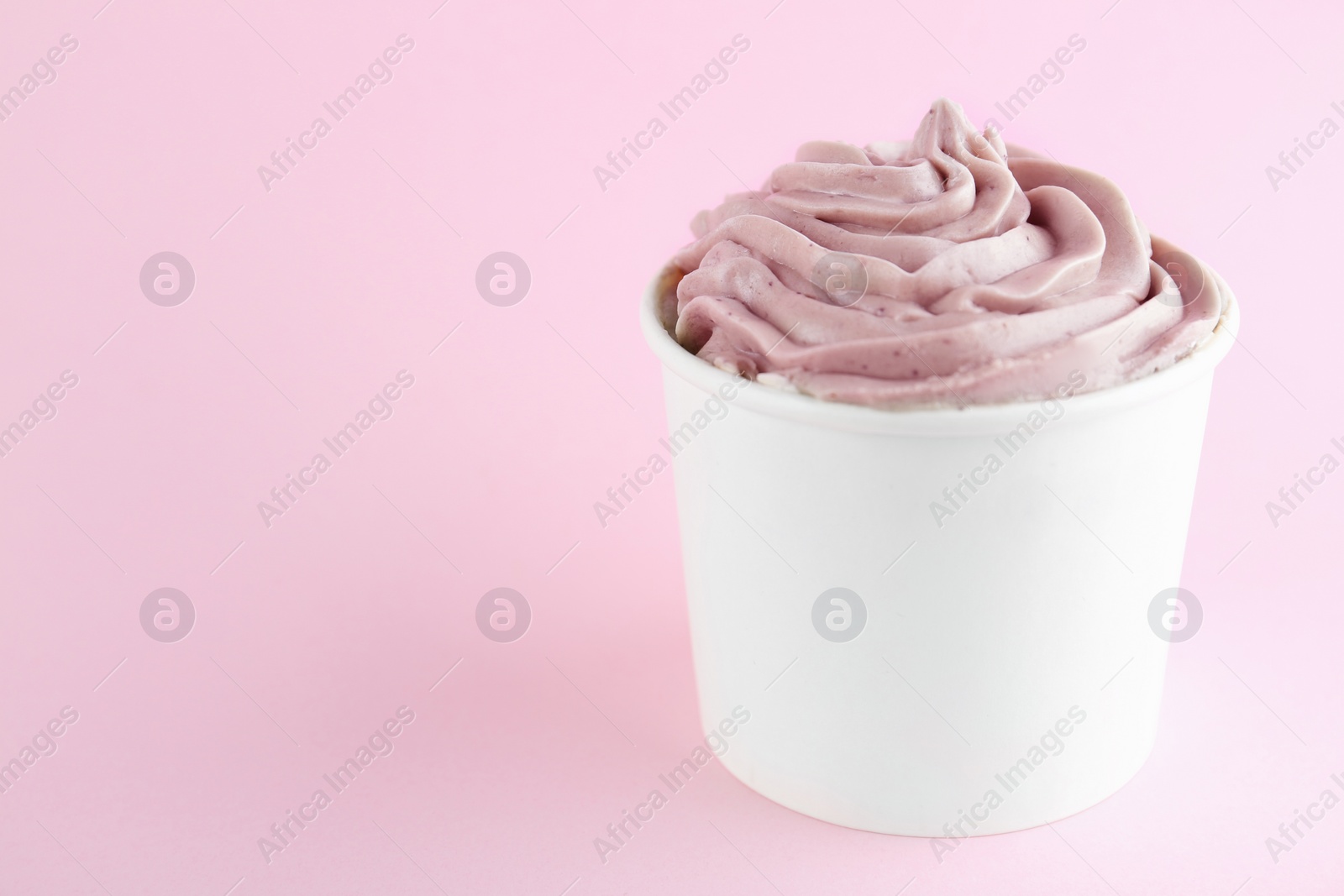 Photo of Cup with tasty frozen yogurt on pink background. Space for text