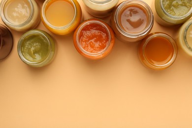 Photo of Jars with healthy baby food on pale orange background, flat lay. Space for text