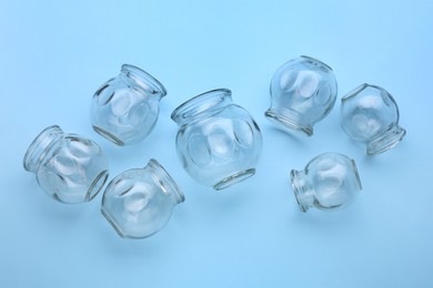 Photo of Many glass cups on light blue background, flat lay. Cupping therapy