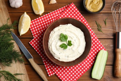 Delicious tartar sauce and ingredients on wooden table, flat lay