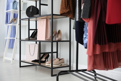 Different stylish shoes and bags on shelving unit in dressing room