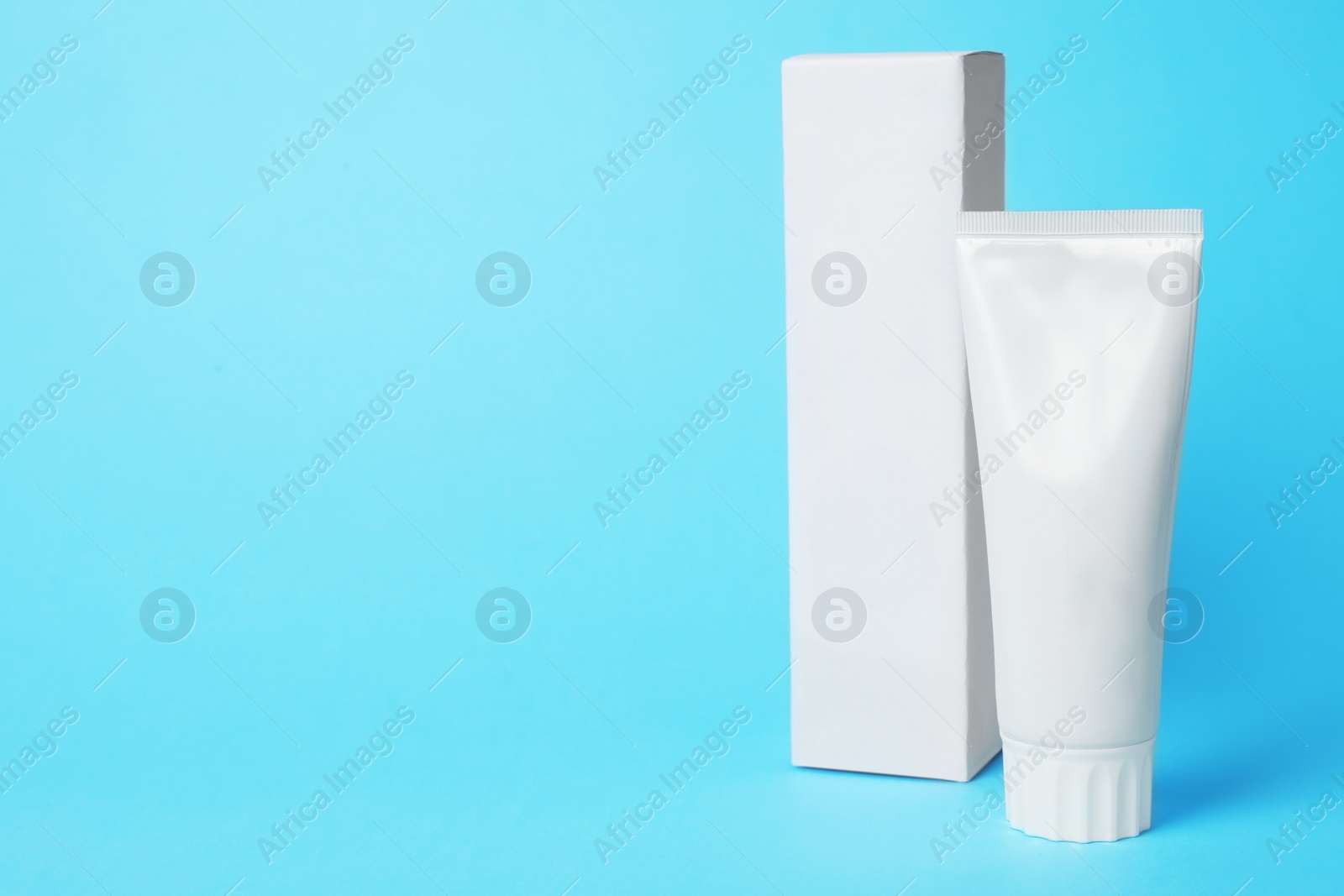 Photo of Blank tube of toothpaste and box on color background. Space for text