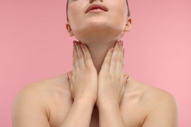 Photo of Woman touching her neck on pink background, closeup