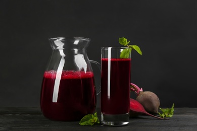 Photo of Fresh beet juice and raw vegetable on dark wooden table