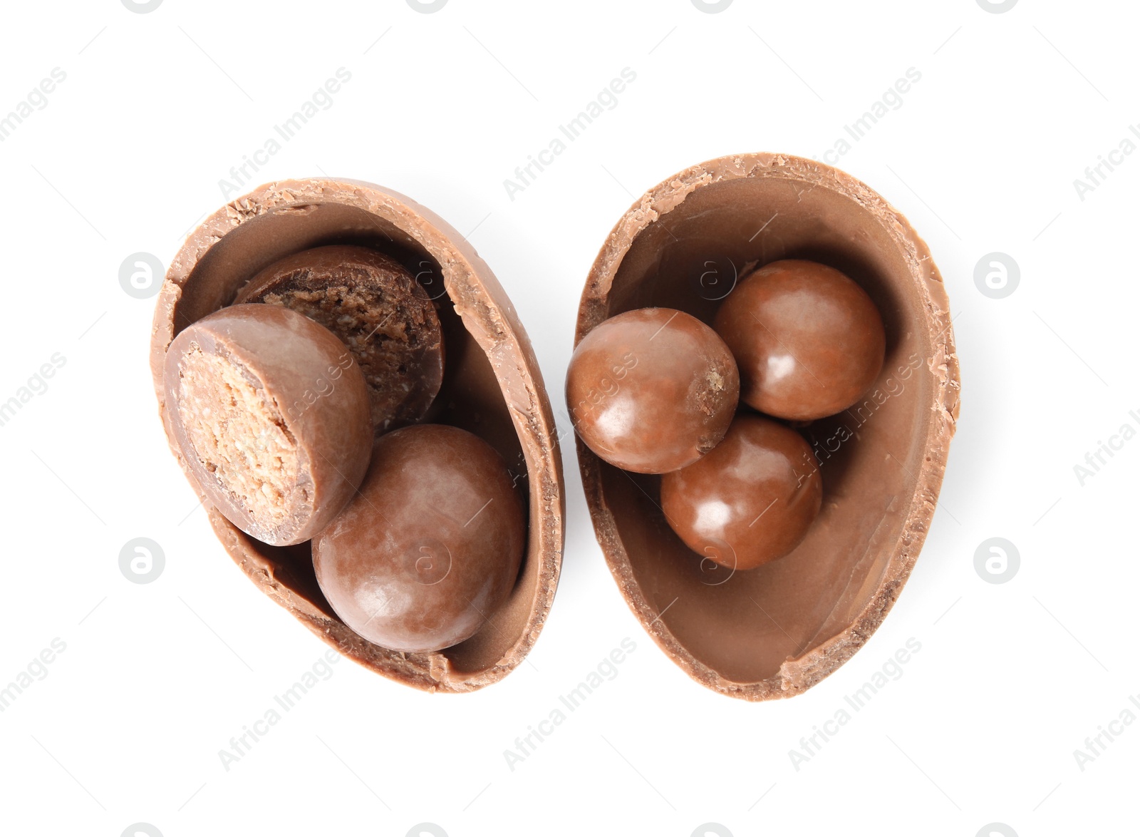 Photo of Broken chocolate Easter egg with candies on white background, top view