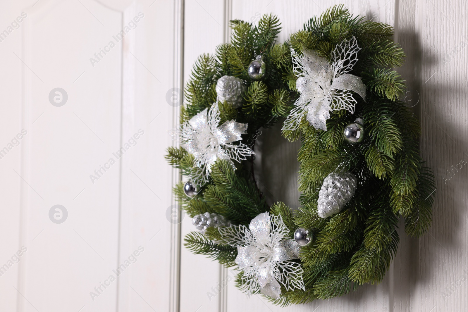 Photo of Beautiful Christmas wreath with festive decor hanging on white door, space for text