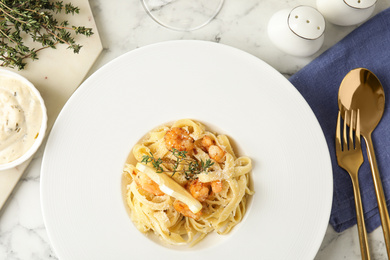 Photo of Delicious pasta with shrimps served on white marble table, flat lay