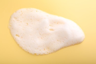 Sample of fluffy foam on yellow background, top view