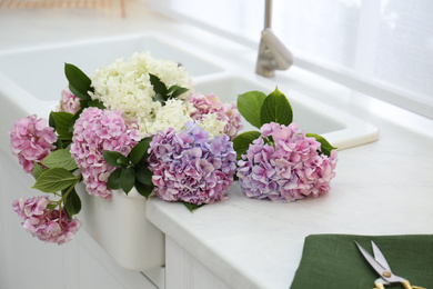 Photo of Beautiful bouquet of hydrangea flowers in sink, closeup