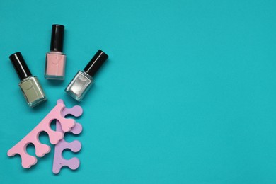 Photo of Nail polishes and separators on turquoise background, flat lay. Space for text