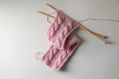 Photo of Pink knitting and needles on beige background, top view