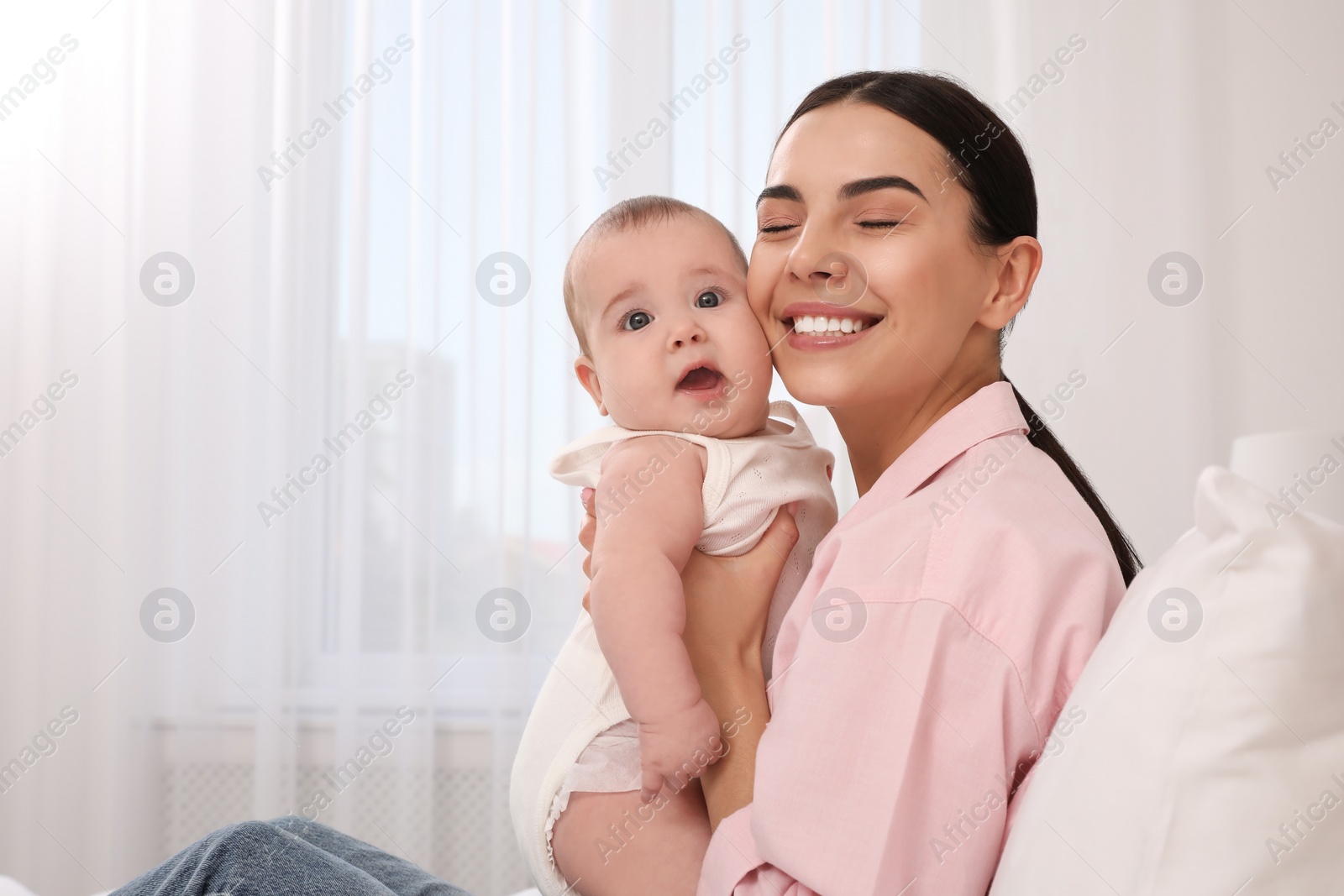 Photo of Young mother with her little baby at home, space for text