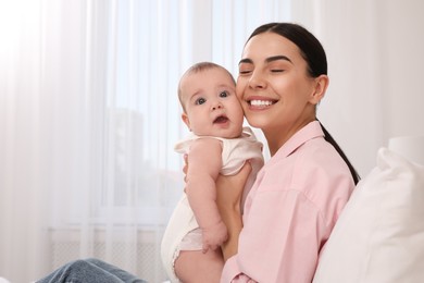 Young mother with her little baby at home, space for text