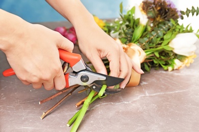 Photo of Female florist pruning stem at table