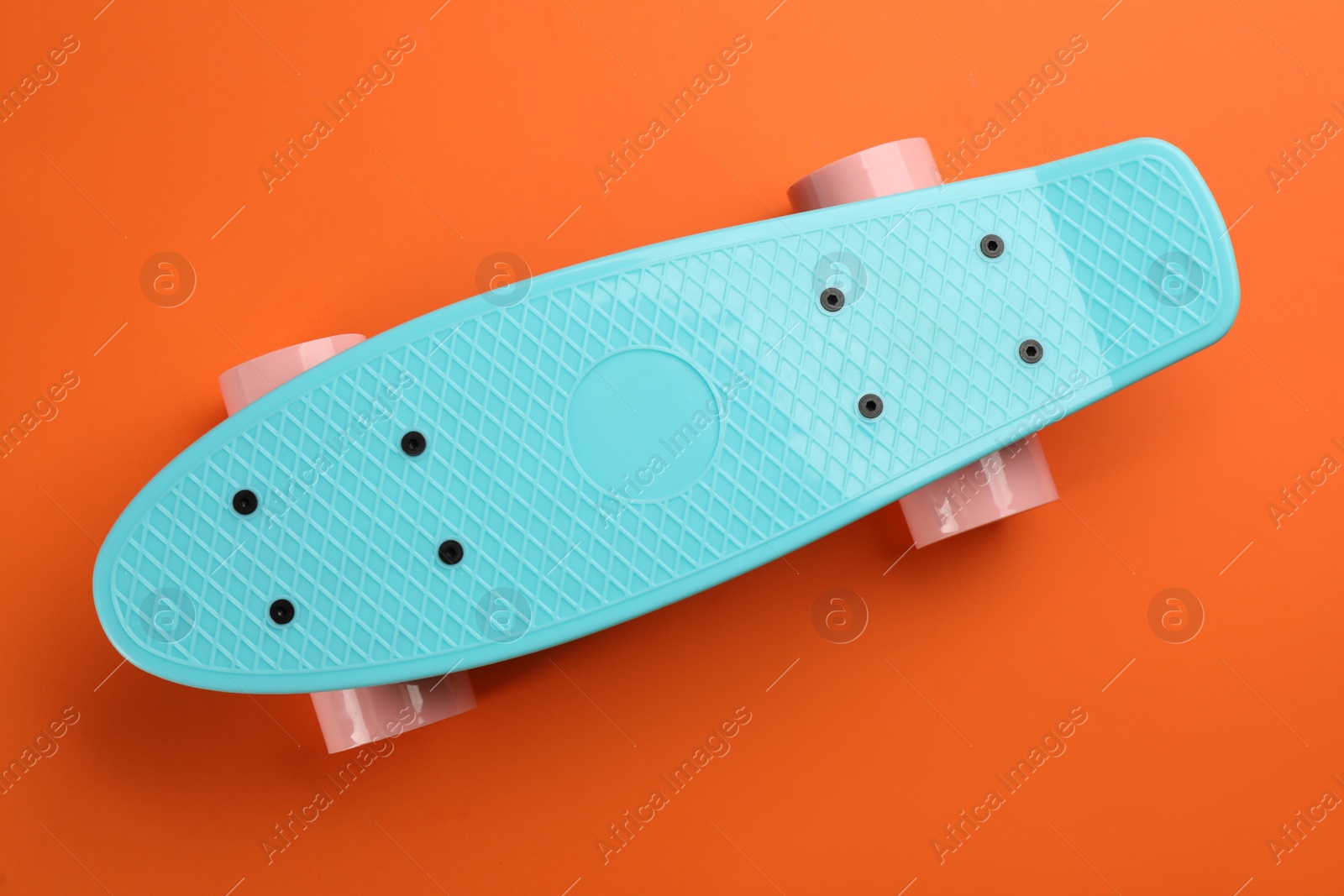 Photo of Turquoise skateboard on orange background, top view